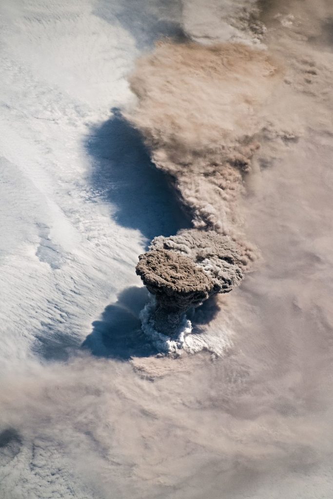 Drone Surveys Map Cooling Lava Fields After an Eruption Ends island volcano with ash cloud above dark lava fields reaching the sea